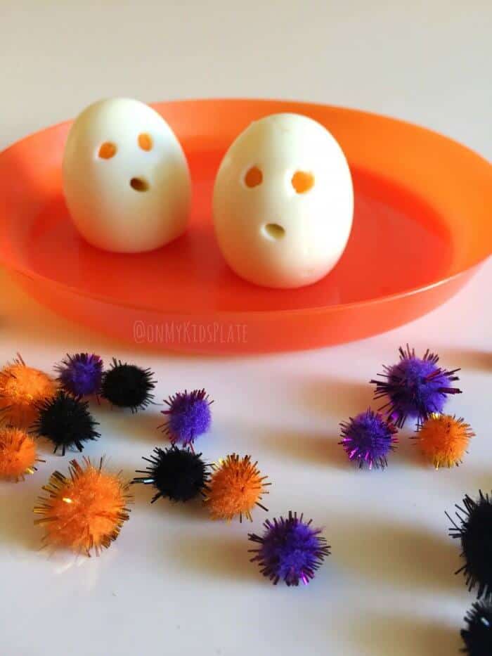 Two hard boiled eggs on a plate made too look like ghousts with eyes and a mouth cut out for a fun snack.