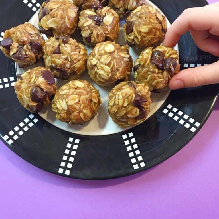 Close up of a child's hand taking a chocolate chip snack bite from a plate