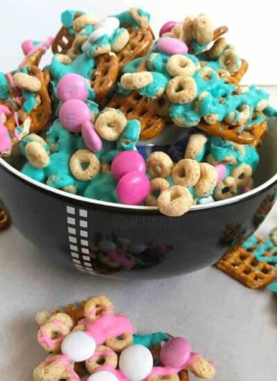 Pretzels mixed with colorful chocolate pieces, cereal pieces and melted colorful chocolate in a bowl