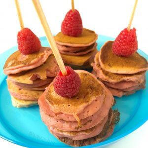 Small pink pancake stacks topped with raspberries on skewers