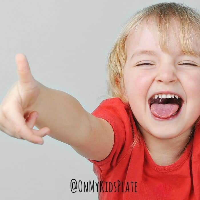 A small child holding her thumb up laughing