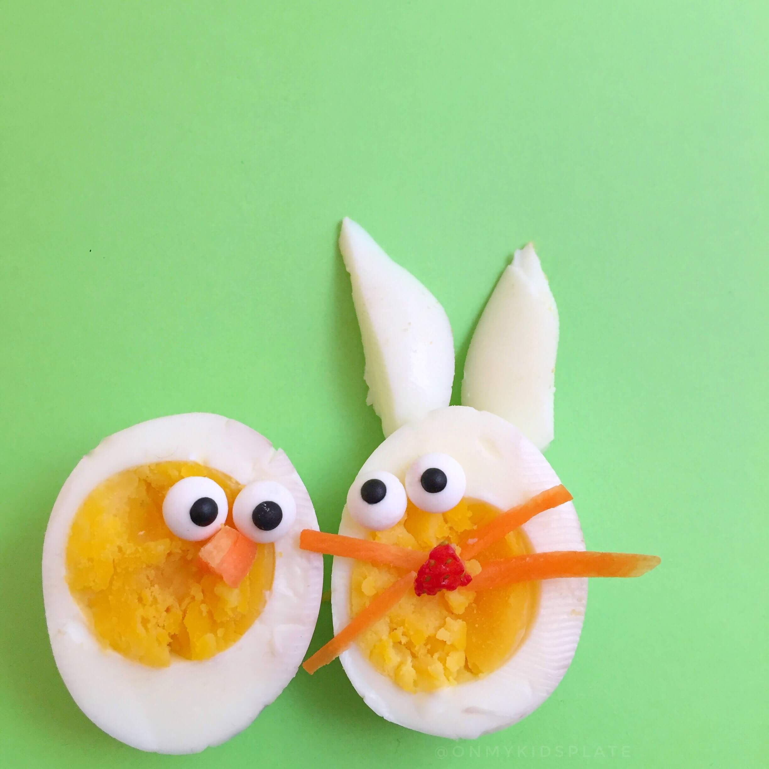 Hard-boiled eggs on a green background cut in half decorated like a rabbit and a chick.