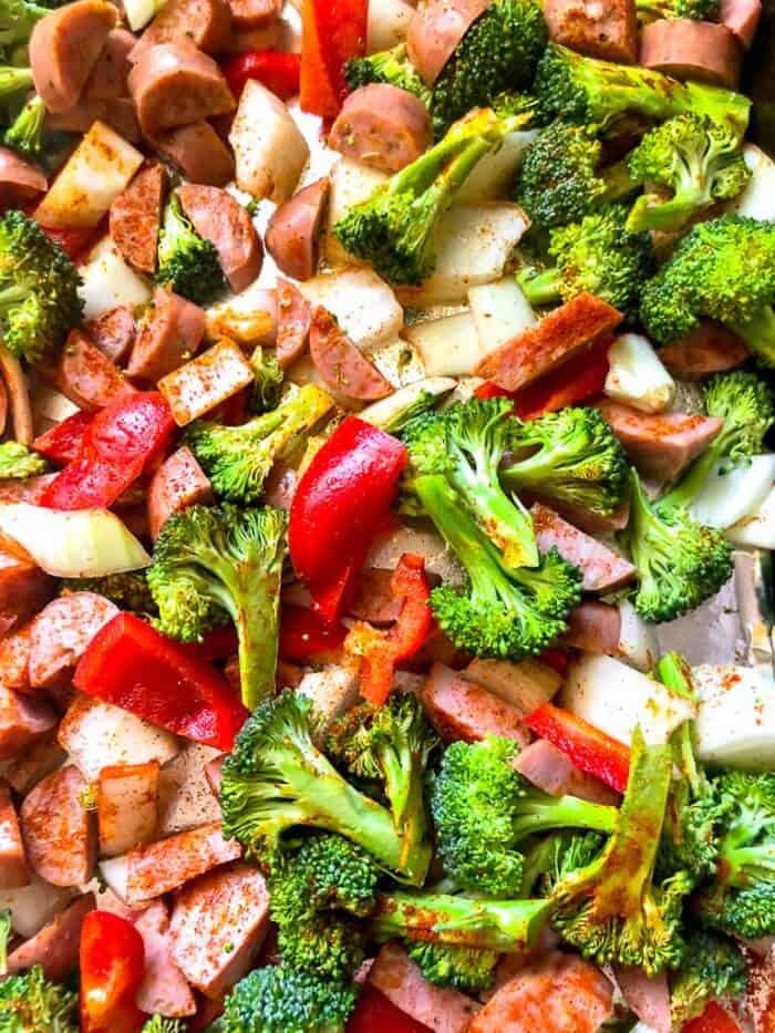 Chicken sausage pieces, broccoli and pepper scattered on a pan