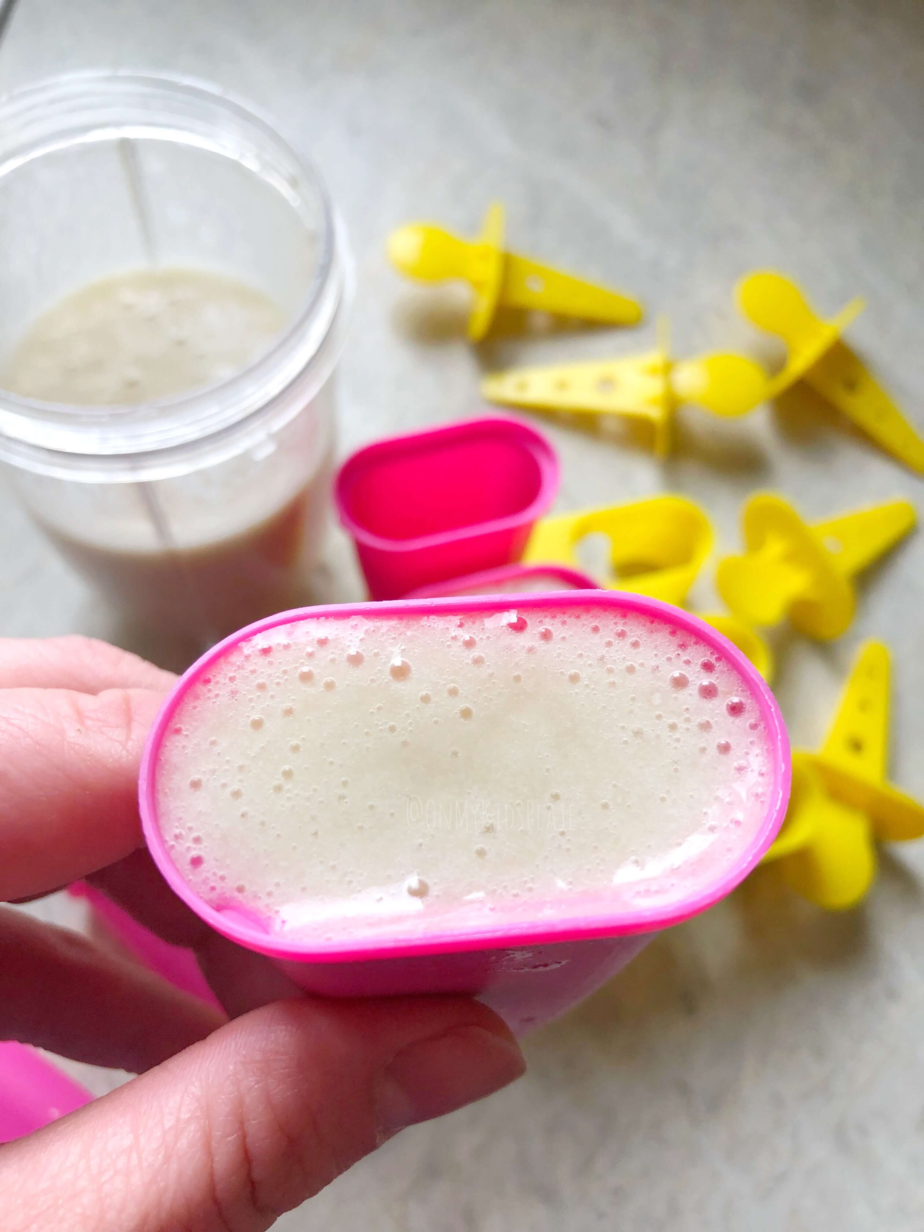 A popsicle mold from overhead being filled with a cup and more popsicle supplies below.