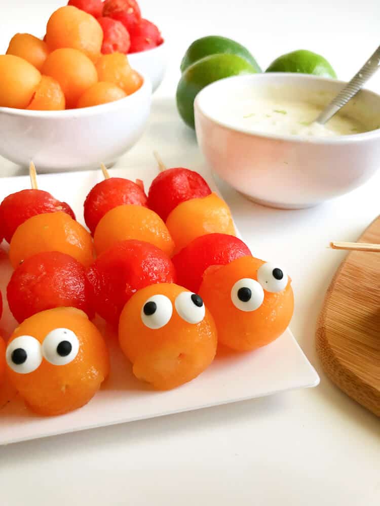 Close up of melon balls decorated to look like caterpillars on sticks