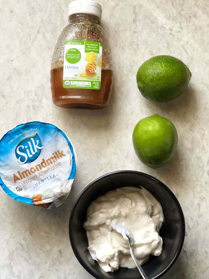 Yogurt, limes and honey with ingredients mixed together in a bowl.