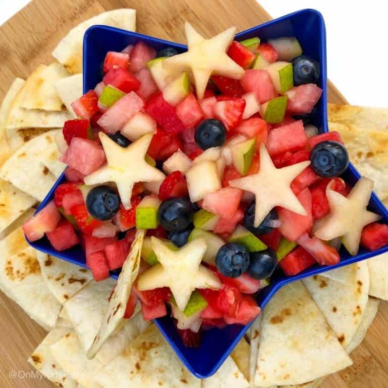 A star-shaped bowl full of fruit salsa with chips around the bowl