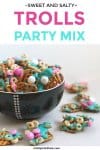 A bowl full of tasty sweet and salty sanck mix sits surrounded by colorful chocolates, Cheerios and pretzels ready for a kid's birthday party.