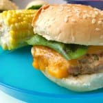 A close up of a turkey burger slider from the side with corn in the background