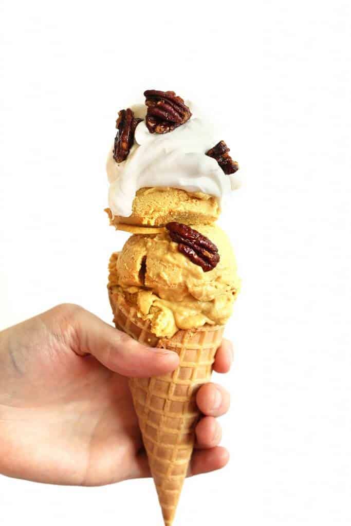 A hand holds a cone with orange ice cream