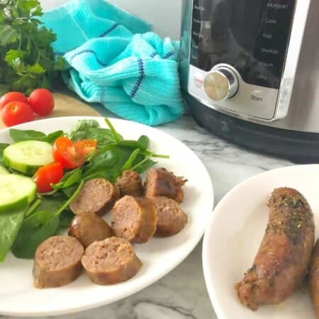 Two plates with sausage, one with salad also and an instant pot in the background