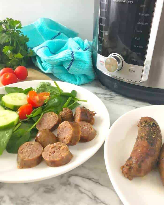 Two plates with sausage, one with salad also and an instant pot in the background