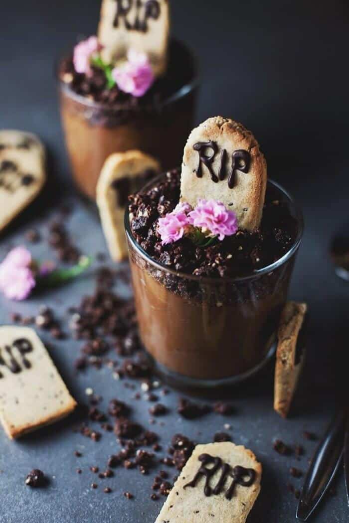 Pudding in a glass with cookie sticking out of it decorated to look like gravestones