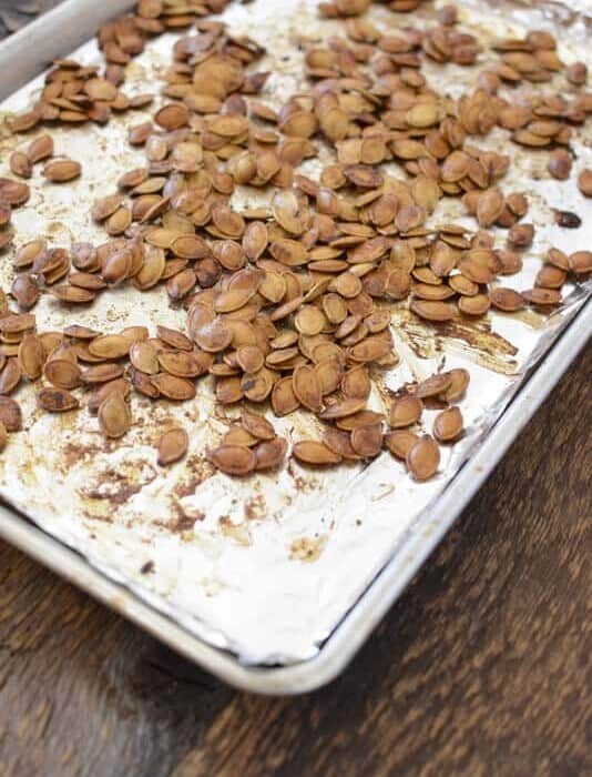 Roasted pumpkin seeds on a baking sheet.