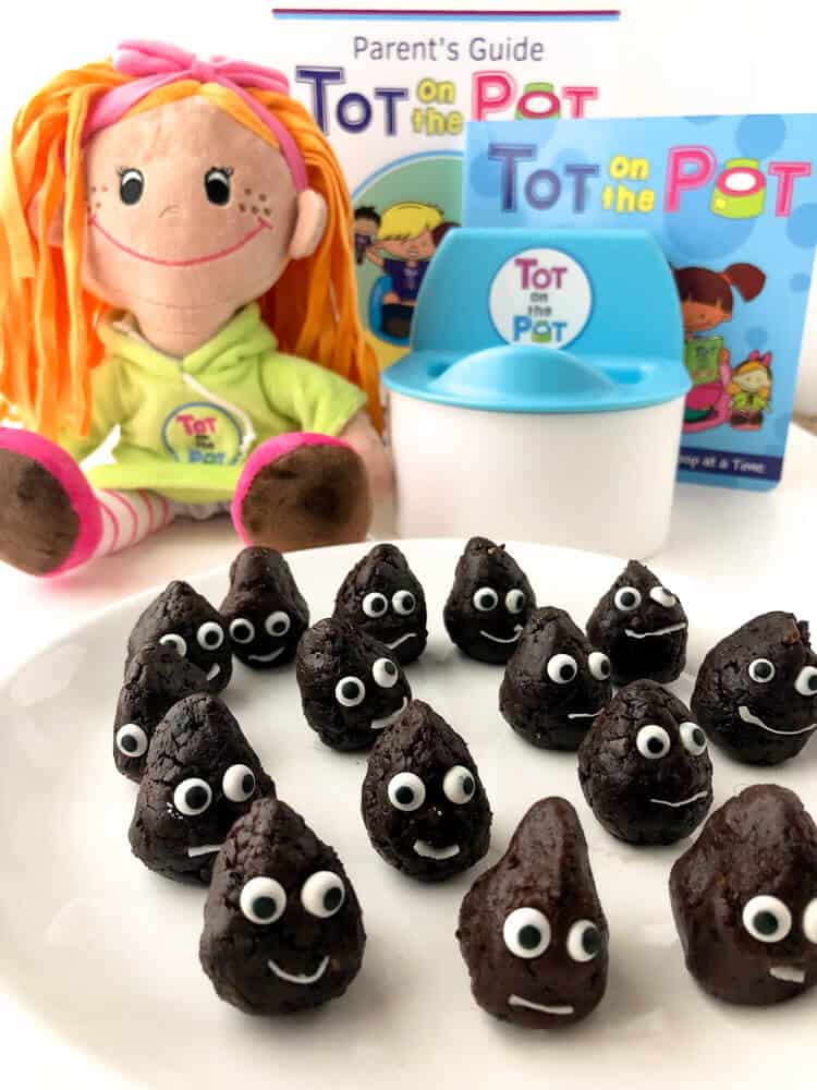 Chocolate snack bites on a plate decorated like they are smiling next to a doll and a doll\'s potty for kids.
