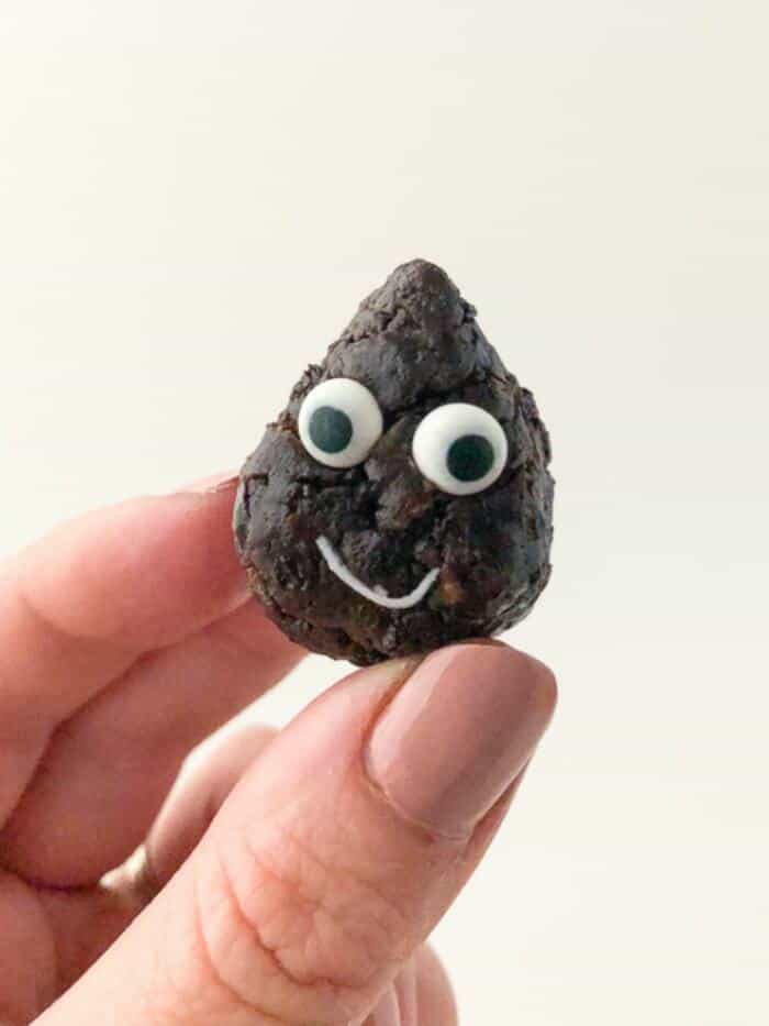 A hand holding a chocolate snack bite with a smiling face