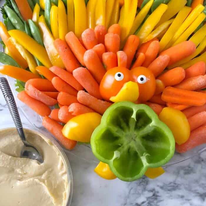 A turkey shaped vegetable platter being filled with hummus dip