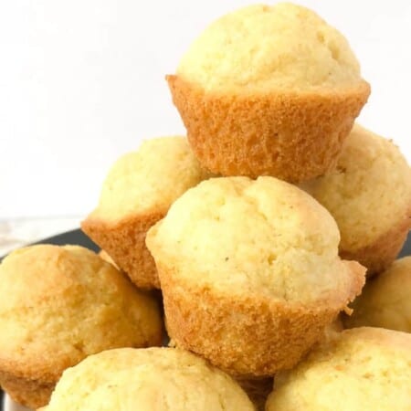 A close up view of a stack of sweet cornbread muffins piled high.