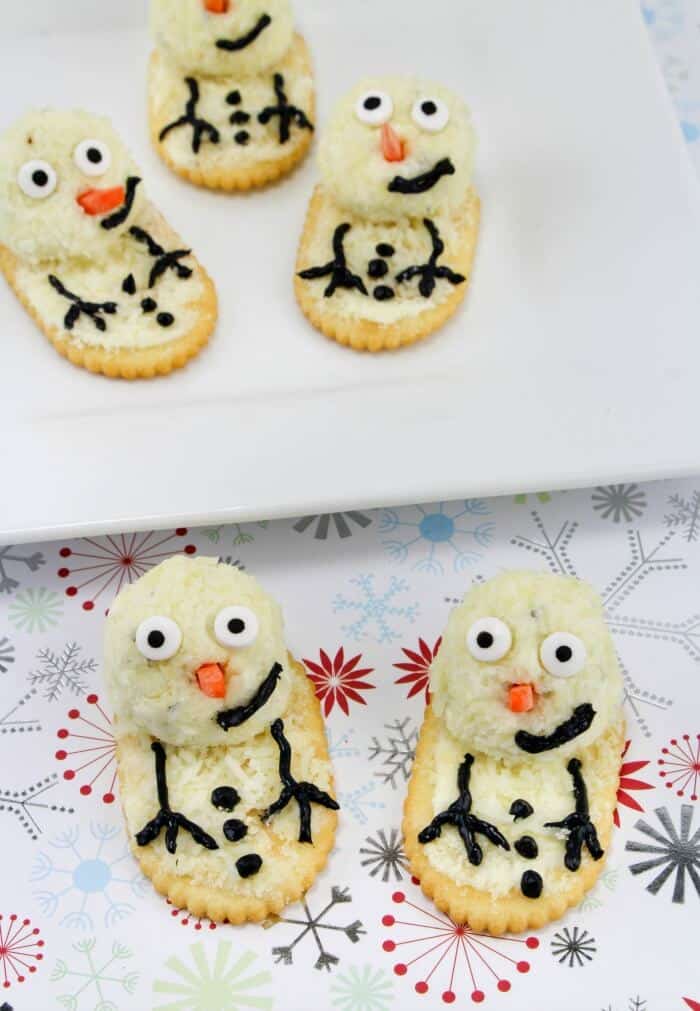 Cheese and cracker decorated to look like snowmen on a serving platter