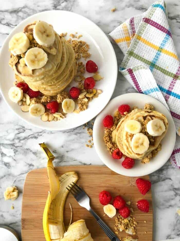 Overhead view of two stacks of almond milk pancakes with fruit and granola