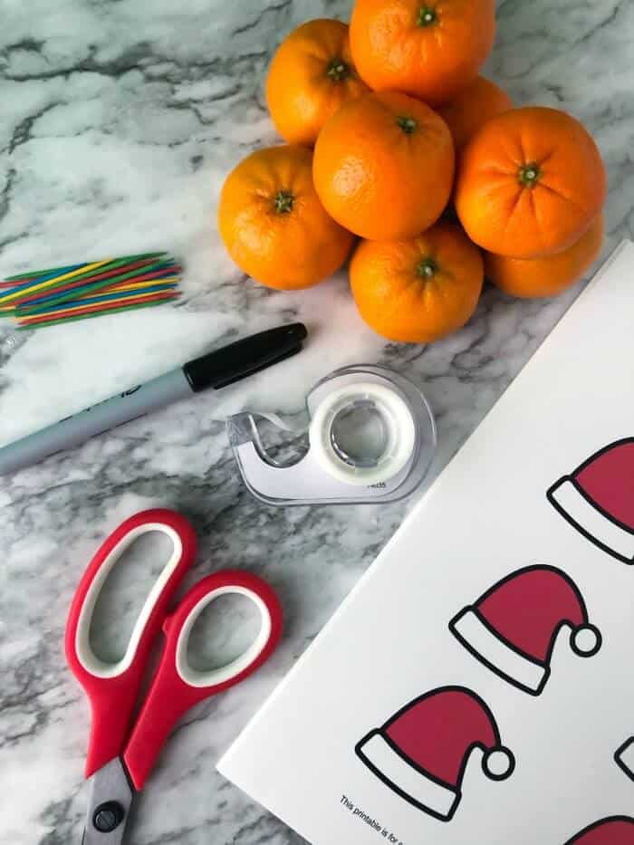 Supplies needed to make Christmas clementines including clementines, toothpicks, sharpie, tape, scissors and printable hat sheet
