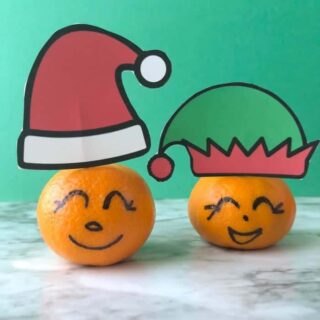 Clementines with faces drawn on the rinf and Santa and elf hats