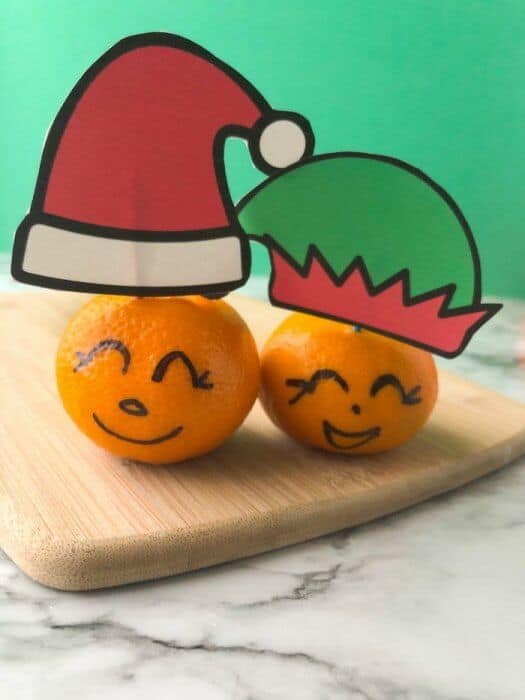 Clementines with faces drawn on and Santa and elf hats