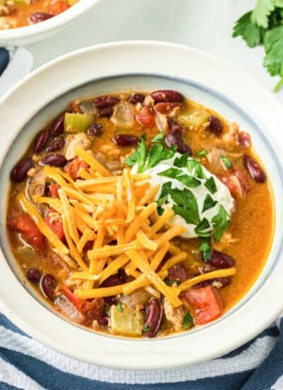 Turkey chili in a bowl topped with cheese, sour cream and parsley