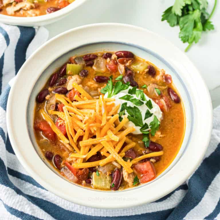 Turkey chili in a bowl topped with cheese, sour cream and parsley