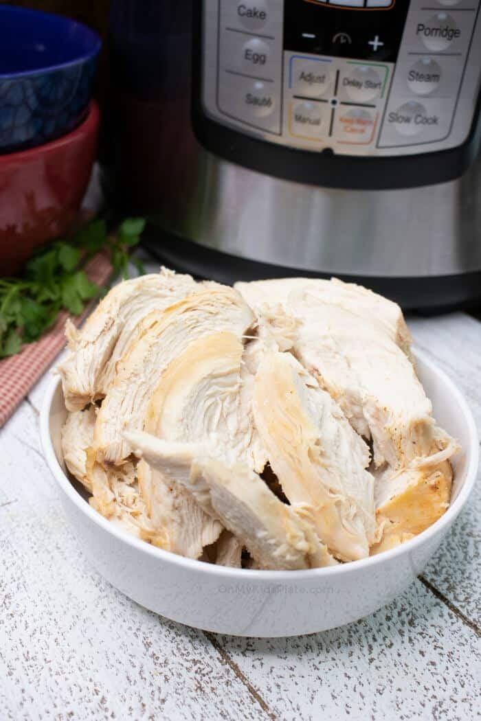 Chicken slices in a bowl with an instant pot in the background