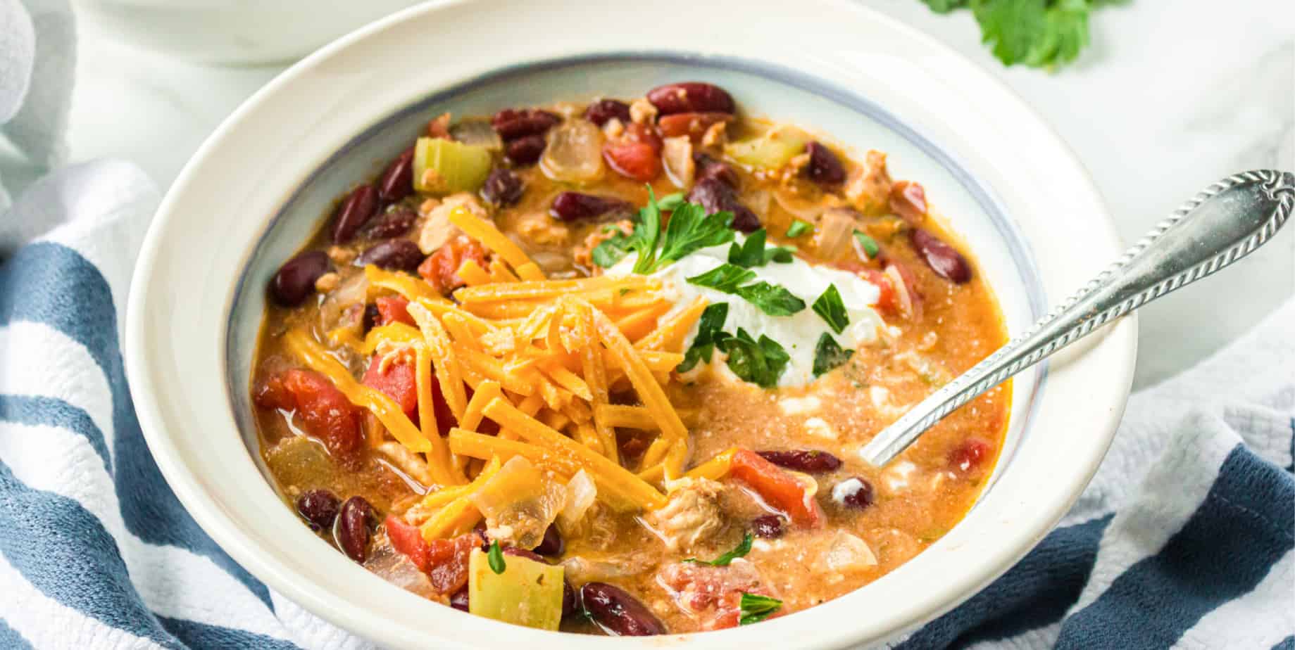 Side view of a bowl of chili with garnish toppings