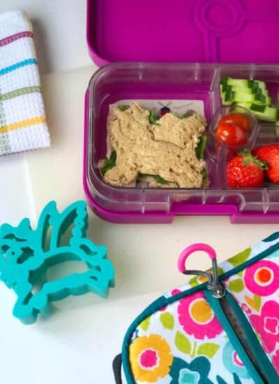 A child's bento lunchbox full of food including a sandwich shaped like a unicorn and a unicorn cookie cutter.