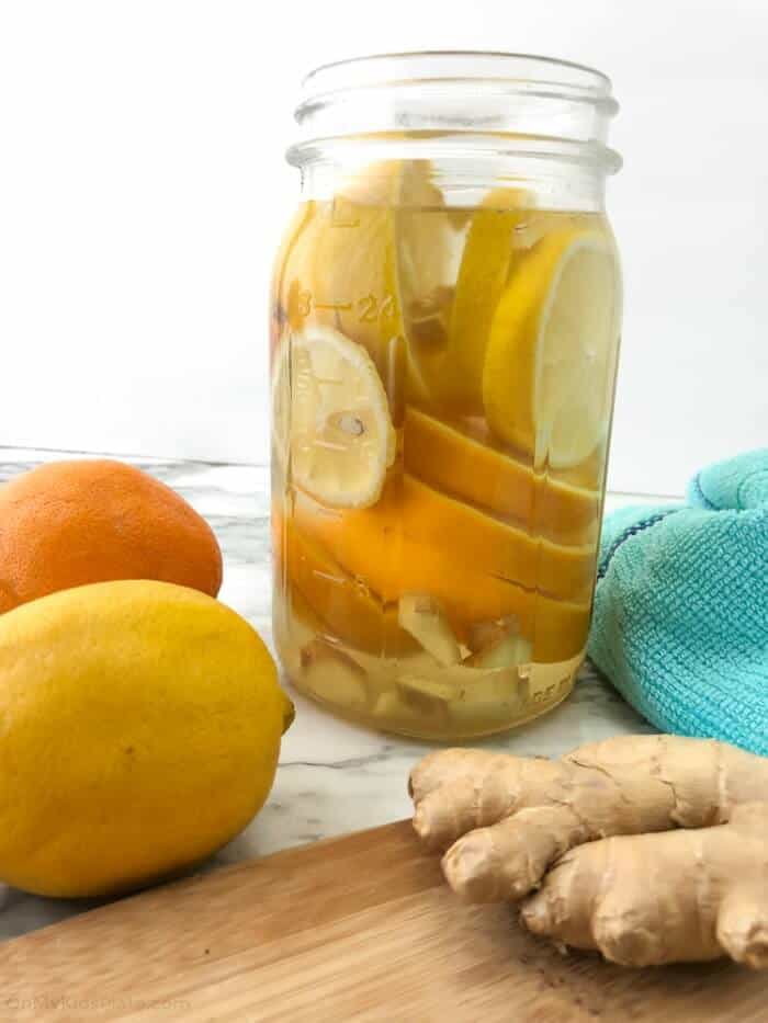 A mason jar full of lemons, oranges and ginger