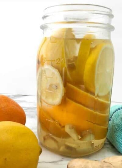 A mason jar full of sliced lemons, oranges and ginger