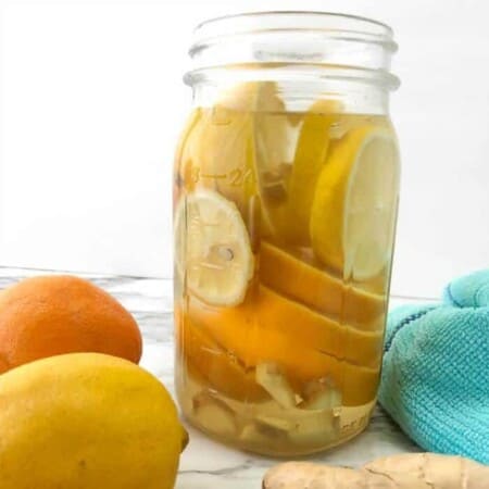 A mason jar full of sliced lemons, oranges and ginger