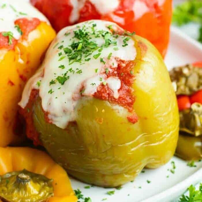 A close up of stuffed peppers on a platter covered in cheese