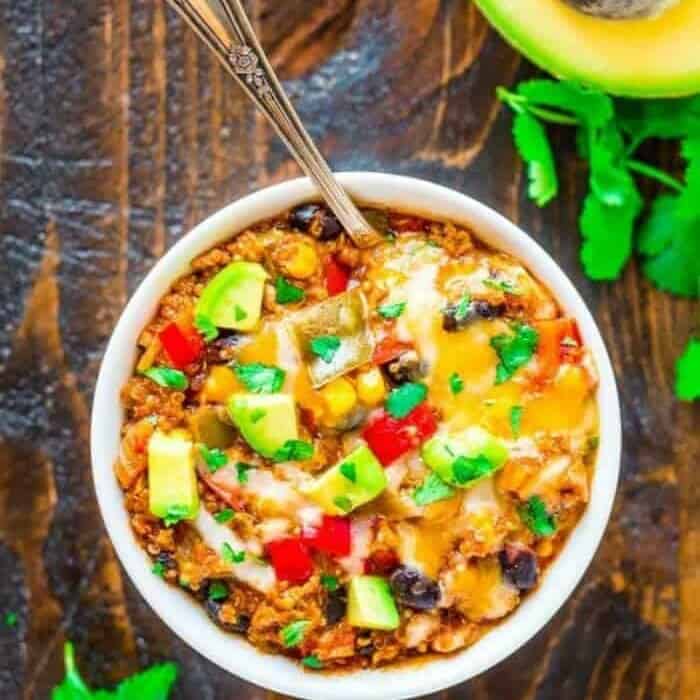 A bowl grom overhead with a spoon full of black beans, cheese, avocado and rice.