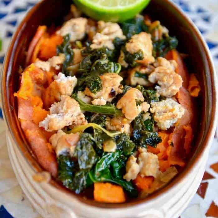 A bowl of cooked turkey, kale and sweet potatoes from above.