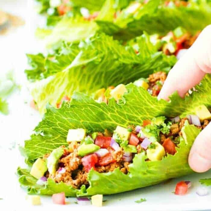 Several pieces of lettuce filled with taco ingredients.