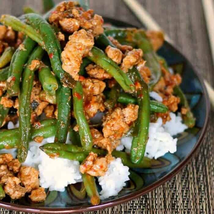 A plate of rice with stir-fried turkey and green beans on top.