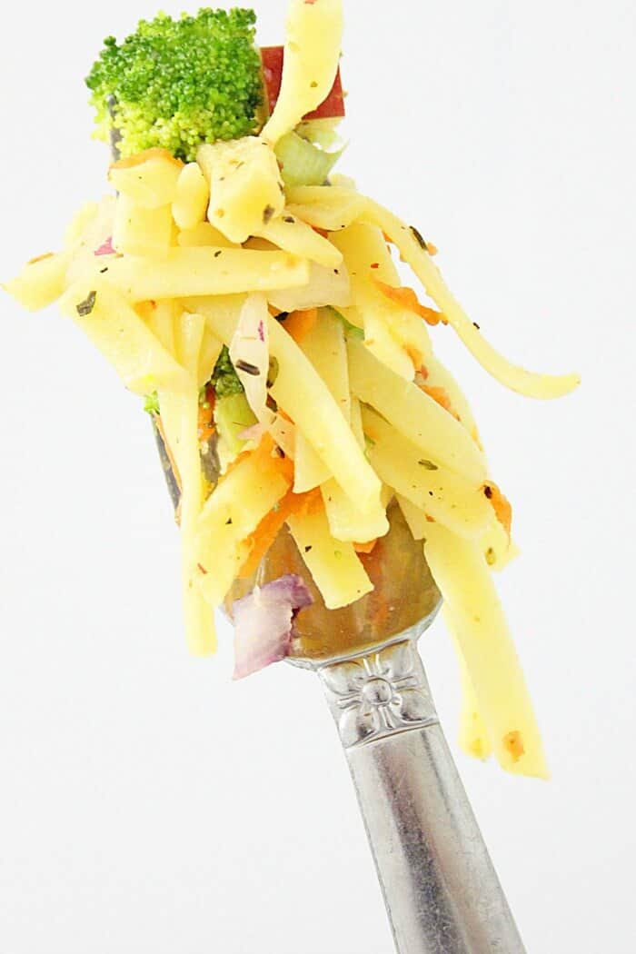 A fork full of broccoli apple salad with pasta up close.