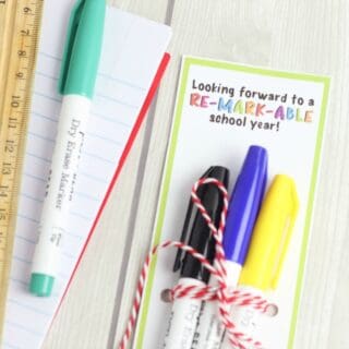 Markers tied to a gift tag next to more school supplies