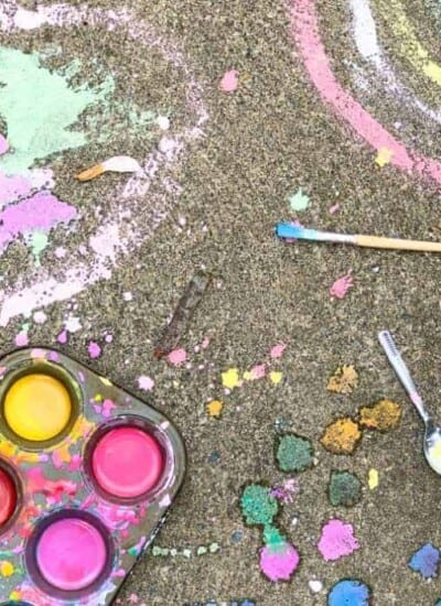 Colorful kid's chalk drawings, a paintbrush and spoon,  and homemade chalk paint in a muffin pan