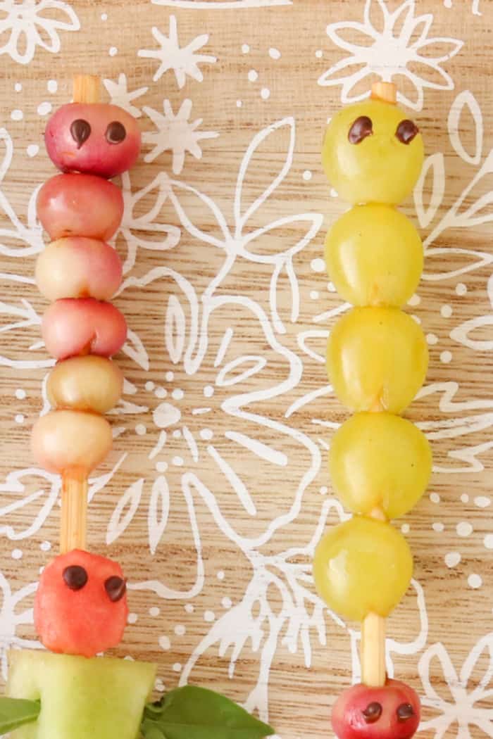 Fruit skewers made of grapes and berries decorated to look like caterpillars