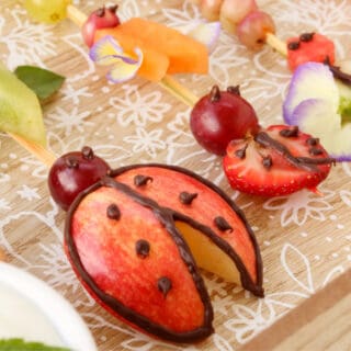 A plate of fruit skewers decorated and shaped like lady bugs and other insects