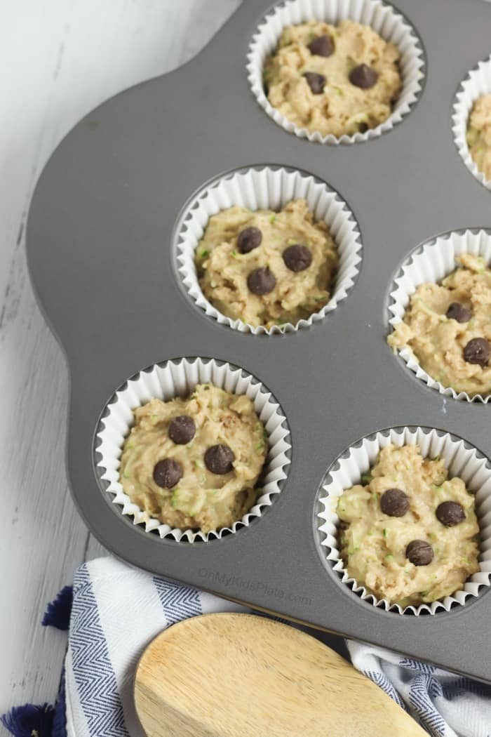 Muffin batter in a muffin pan with chocolate chips on top