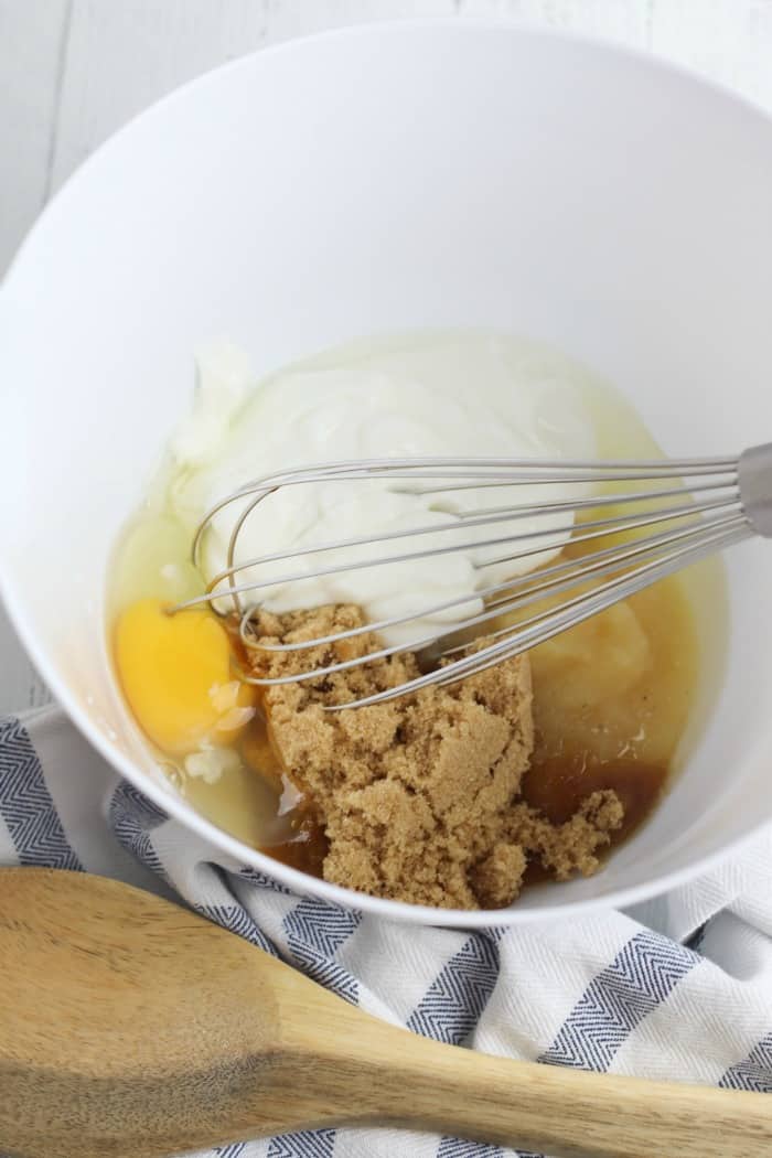 A bowl of brown sugar, egg and applesauce being mixed with a whisk