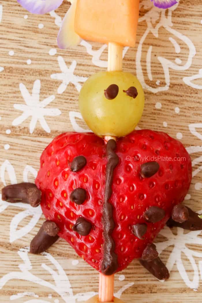 A ladybug close up made of strawberry, grape and decorated with chocolate