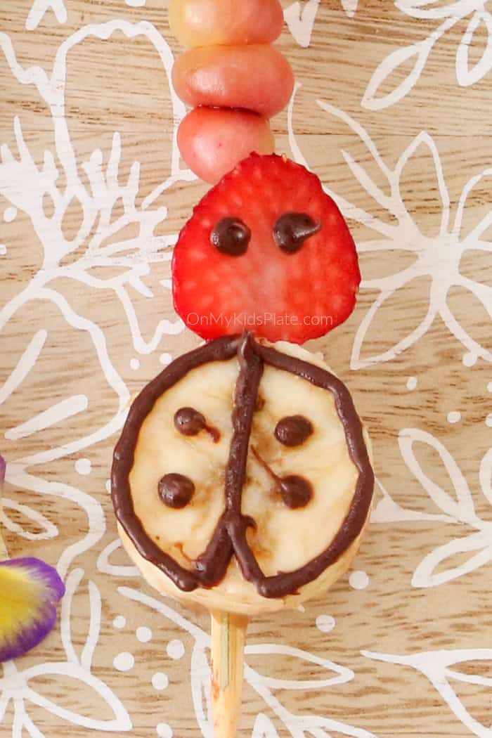 A lady bug made of banana, strawberry and chocolate on a skewer close up