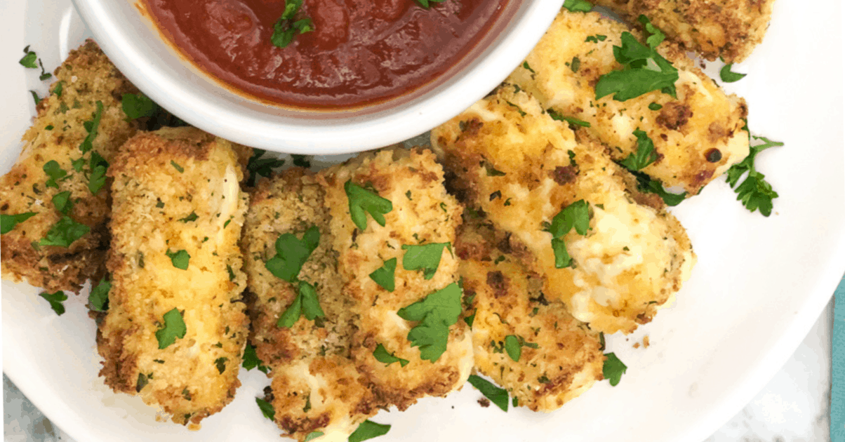 Mozzarella sticks next to a small bowl of marinara sauce.